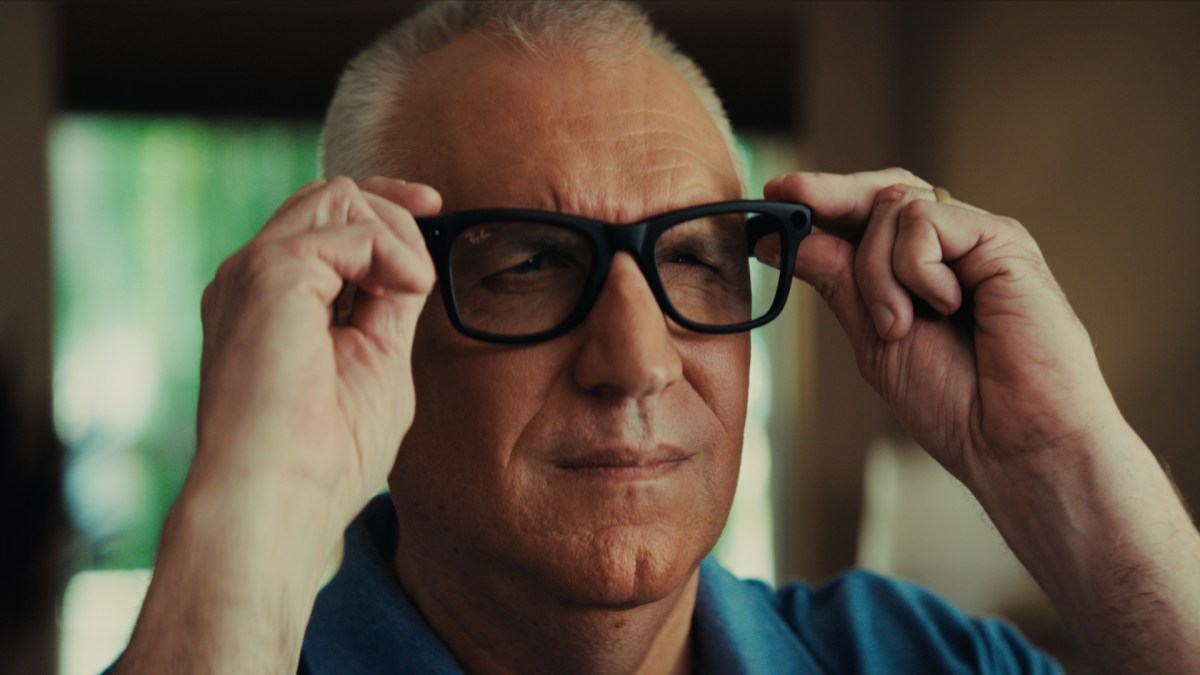 Ian Torrie, a man with sight impairment, smiles while wearing black Meta smart glasses and a patterned shirt.