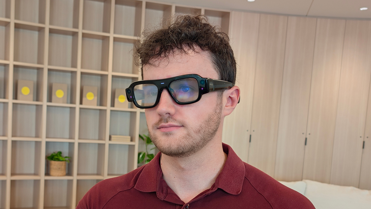 A person wearing Snap Specs smart glasses indoors, viewed from a slightly upward angle.